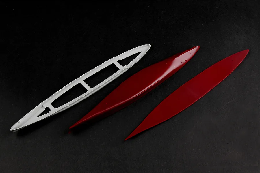 Three plastic model ship hull components from a Trumpeter 1/700 scale battleship kit, including a white internal frame and two red hull pieces.