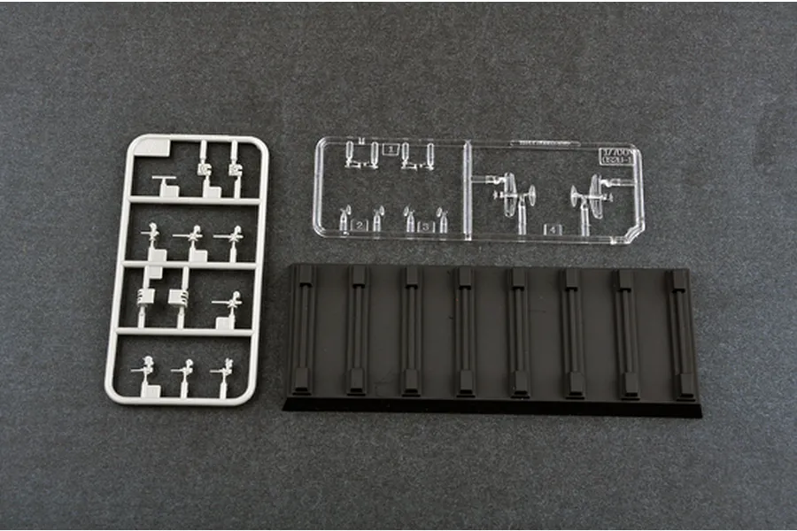 Plastic model kit parts including a grey sprue of small components, a clear sprue of aircraft parts, and a black display stand base.