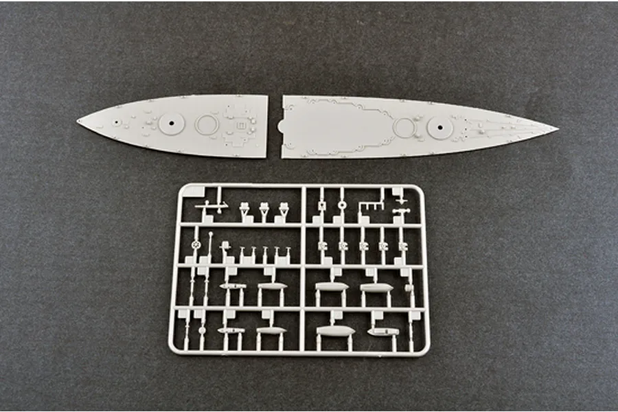 Two grey plastic battleship deck sections and a sprue of small model parts on a dark grey background.