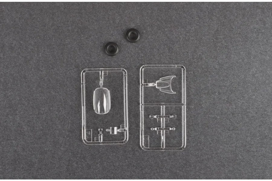 Clear plastic model kit sprues and two small black rubber rings on a dark grey background.