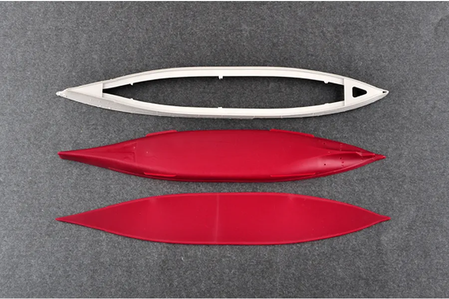 Top-down view of three unpainted plastic model ship hull components for a 1/700 scale battleship kit, laid out on a grey surface.