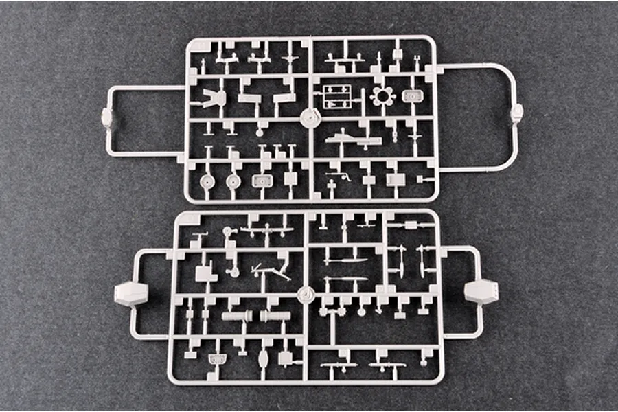 Two grey plastic model kit sprues containing various small battleship parts laid flat on a dark grey surface.