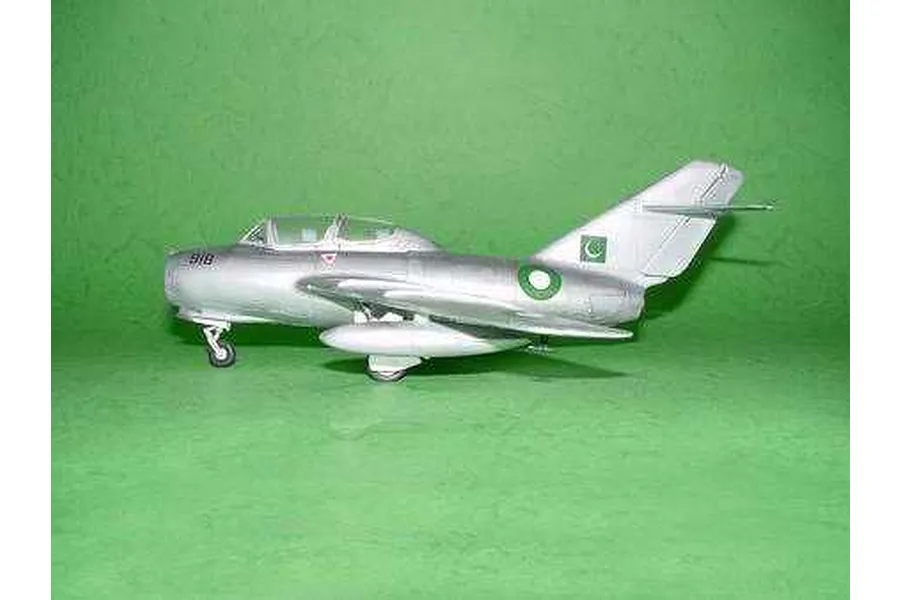A side view of a silver MiG-15 UTI model aircraft with Pakistani Air Force markings, displayed on a green background.