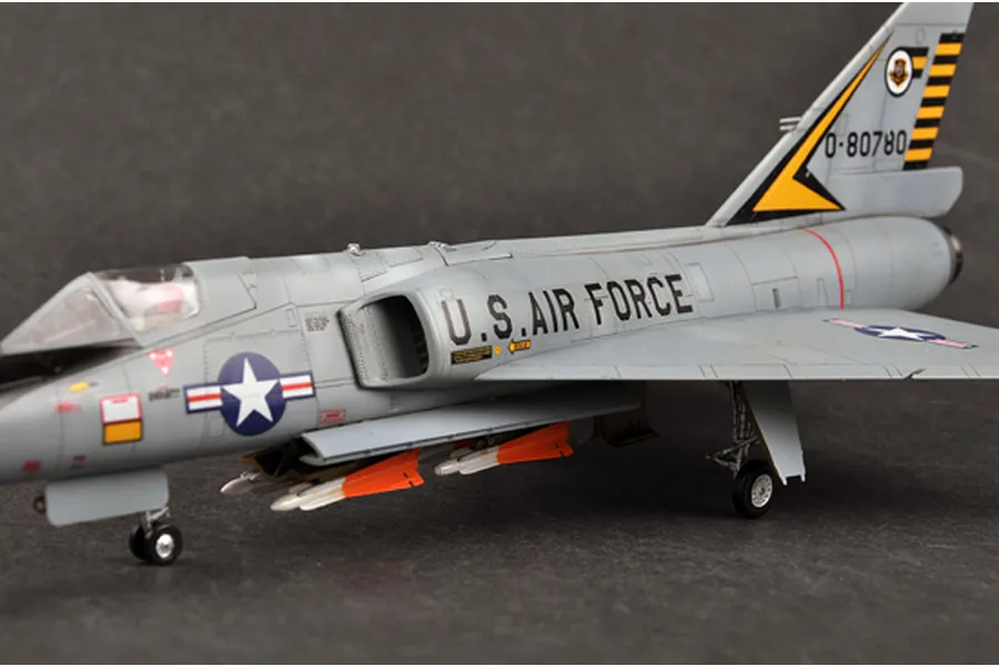A side-profile view of a 1/72 scale plastic model of a US Air Force F-106A Delta Dart fighter jet, featuring grey paint, US insignia, and orange missiles.