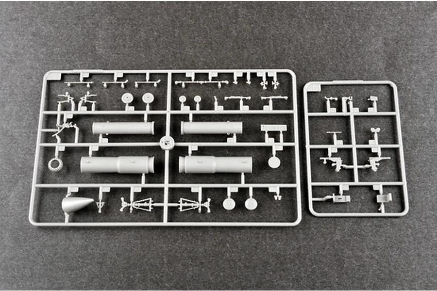 Two grey plastic model kit sprues containing various aircraft parts like landing gear, wheels, and cylindrical components on a dark grey background.