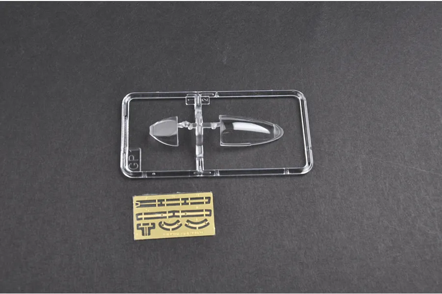 Clear plastic sprue containing aircraft canopy parts and a small photo-etched brass fret for a model kit.
