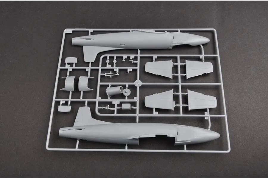 A grey plastic sprue containing parts for a 1/48 scale model aircraft, including fuselage halves and wing sections, set against a dark grey background.