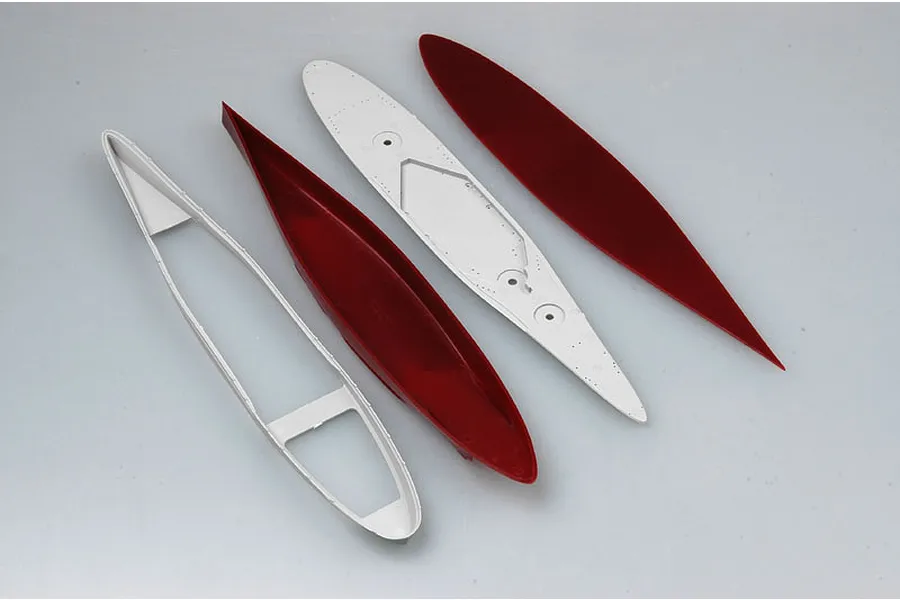 Four unpainted plastic model ship hull components arranged on a plain grey background.