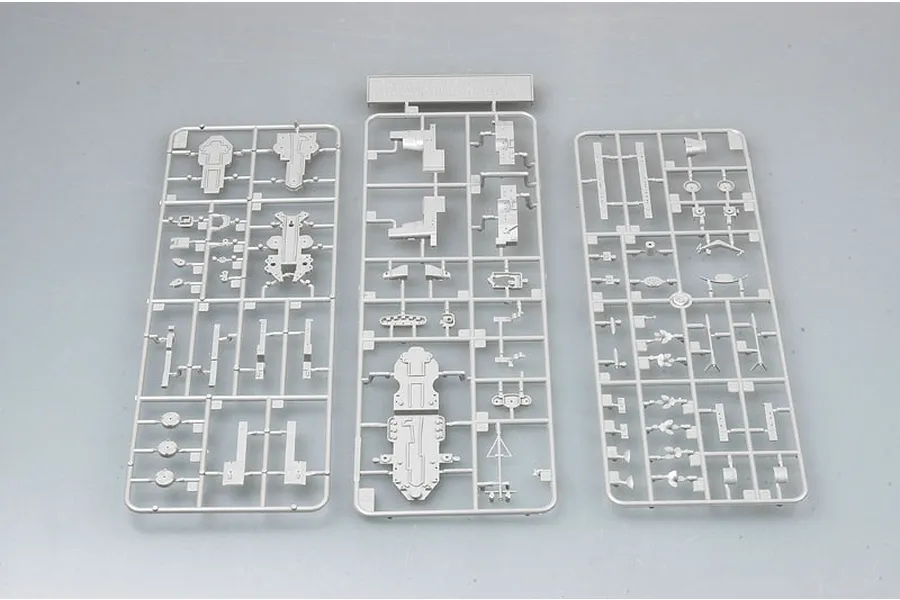 Three grey plastic model kit sprues containing various ship parts laid out on a plain grey surface.