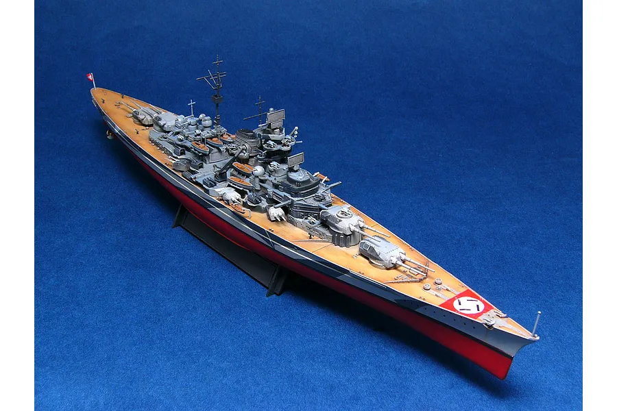 A fully assembled and painted 1/700 scale model of the German battleship Tirpitz, shown from a high-angle perspective against a blue background.
