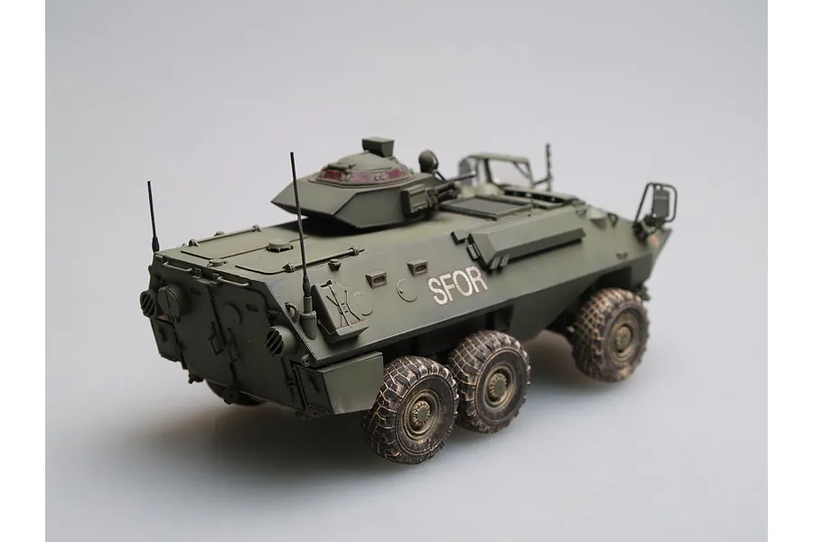A 1/35 scale model of a Canadian Grizzly AVGP armoured vehicle, painted in olive drab with SFOR markings, viewed from the rear three-quarter angle.