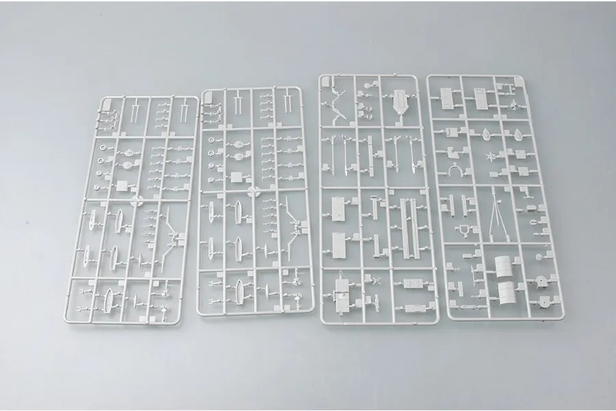 Four grey plastic model kit sprues containing various ship parts laid out on a plain grey background.