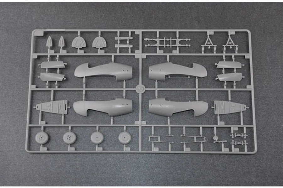 A grey plastic sprue containing various aircraft model parts, including fuselage halves, wheels, and landing gear components.