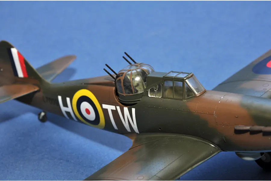 A close-up side view of a 1/48 scale Boulton Paul Defiant model aircraft, showing the rear gun turret and RAF camouflage markings on a blue background.