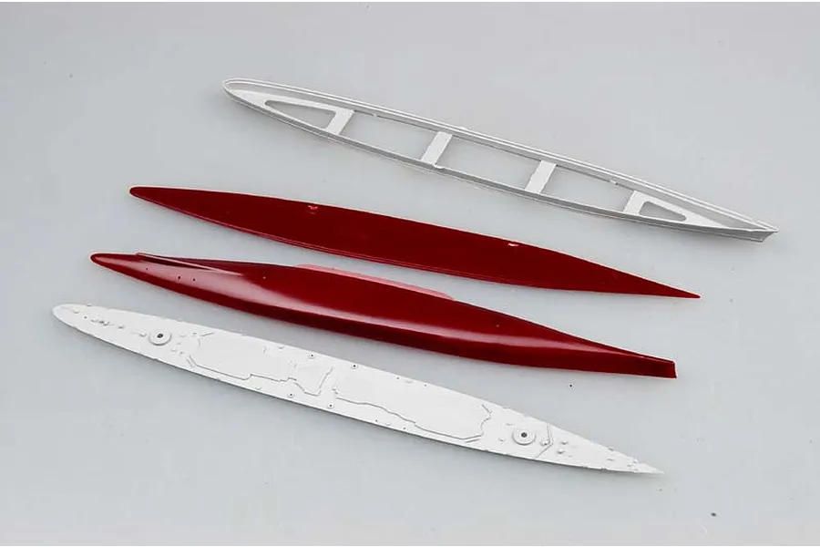 Four unpainted plastic model ship hull and deck components from a Trumpeter 1/700 scale model kit, arranged on a plain white background.