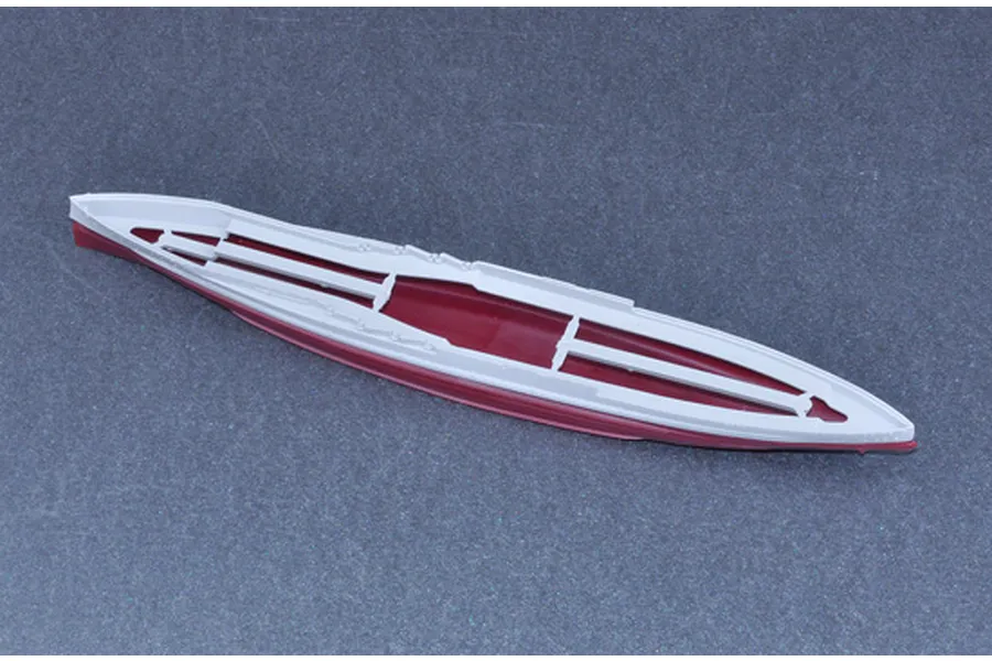 A plastic model ship hull piece, showing a red lower hull and white upper deck structure, viewed from above against a dark grey background.