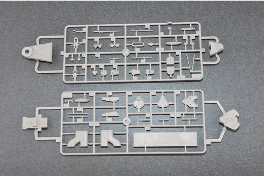 Two grey plastic model kit sprues containing various ship parts for a 1/700 scale model, laid out on a dark grey surface.