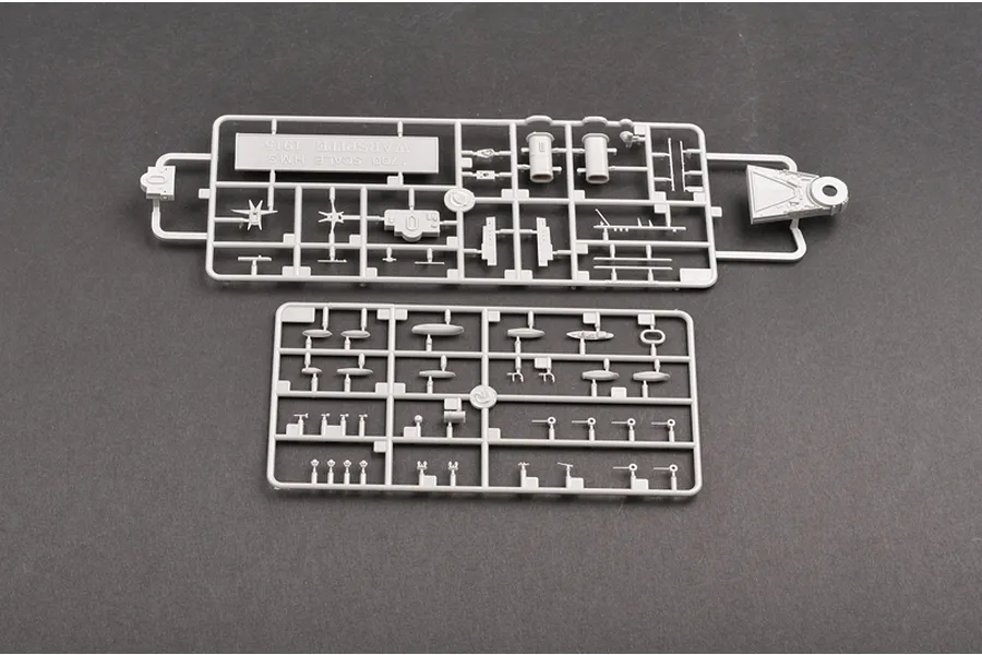 Two grey plastic model kit sprues for the Trumpeter 1/700 HMS Warspite 1915 battleship model, laid out on a dark grey surface.