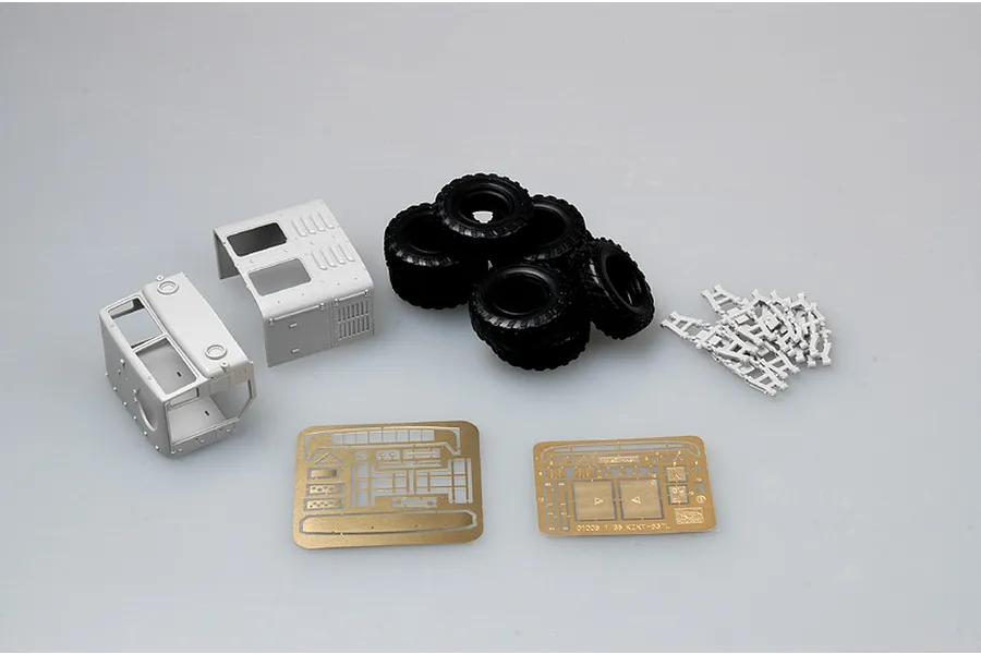 Unassembled plastic model kit parts for a 1/35 scale KZKT-537L truck, including grey plastic cab sections, black rubber tires, and photo-etched metal sheets.