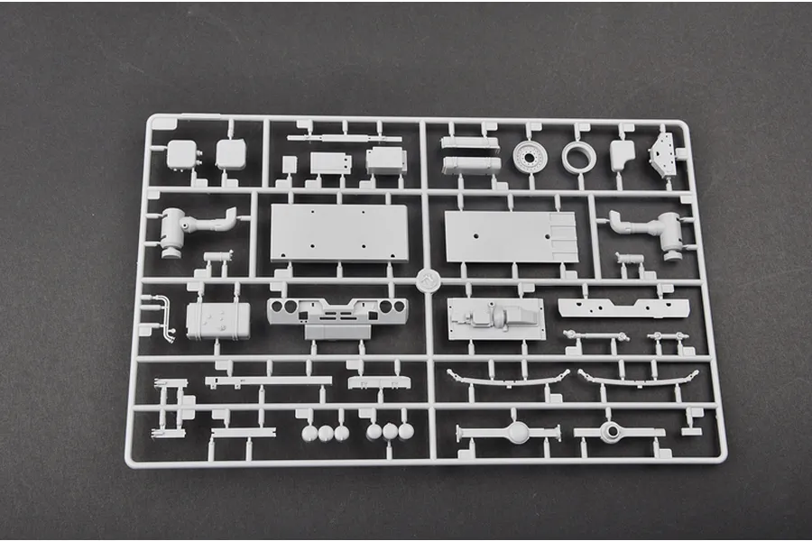 A grey plastic sprue containing various unpainted model parts for a 1/35 scale military vehicle kit, laid out on a dark grey surface.
