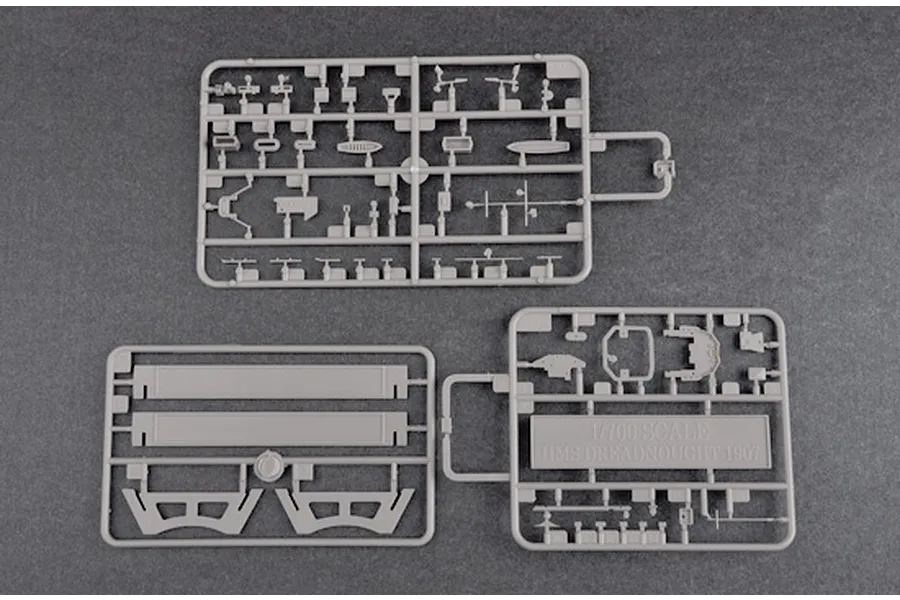 Three grey plastic model kit sprues for a 1/700 scale HMS Dreadnought 1907 battleship model on a dark grey background.