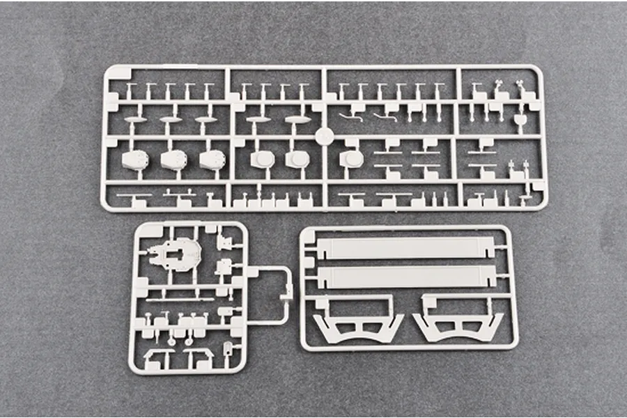 Three grey plastic model kit sprues containing various ship parts laid out on a dark grey surface.