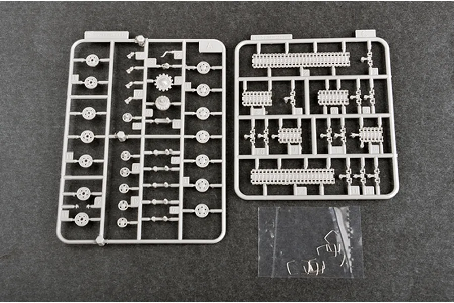 Two grey plastic model kit sprues and a small bag of metal parts for a 1/72 scale tank model on a dark grey background.