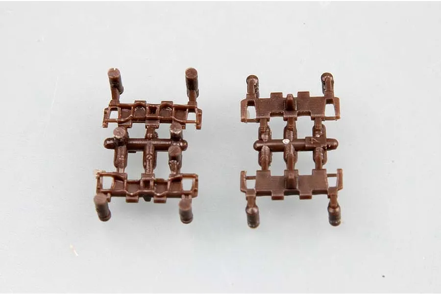 Two brown plastic tank track links from a model kit, shown from top and bottom views on a light grey background.