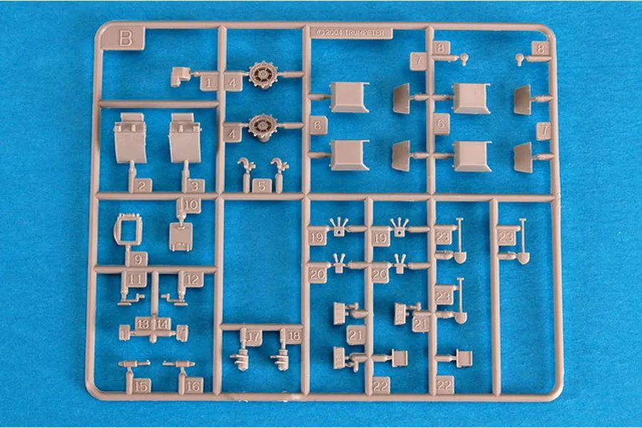 A plastic model kit sprue labeled B, containing various small grey parts for a 1/72 scale military vehicle model, set against a blue background.