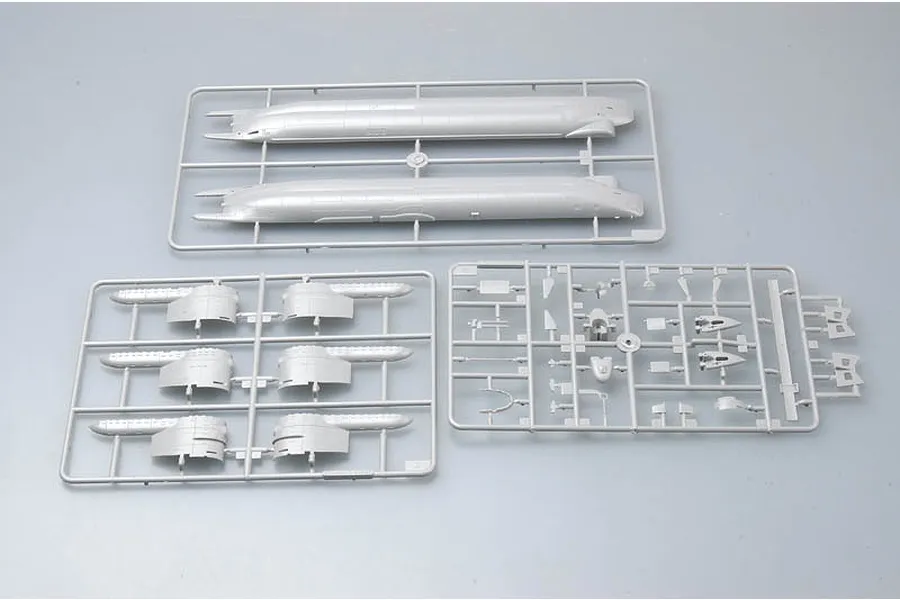 Three grey plastic model kit sprues for a 1/144 scale German Type XXIII U-Boat, showing hull sections and various small components on a light grey background.