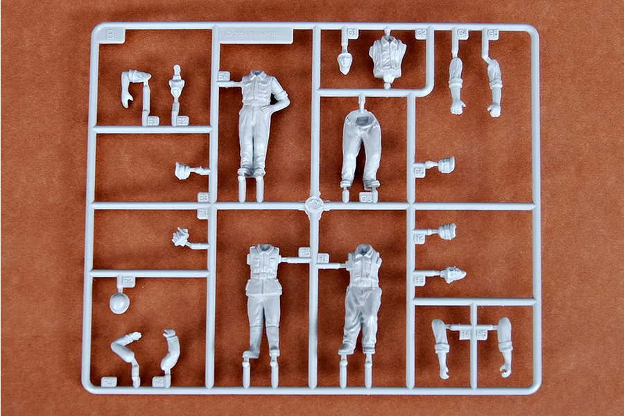 A grey plastic sprue containing various unpainted model soldier parts for a 1/35 scale German artillery crew kit.