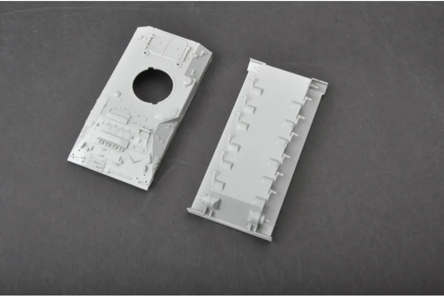 Two unpainted grey plastic model tank hull parts from a Trumpeter 1/72 scale British Warrior model kit, viewed from above on a dark surface.