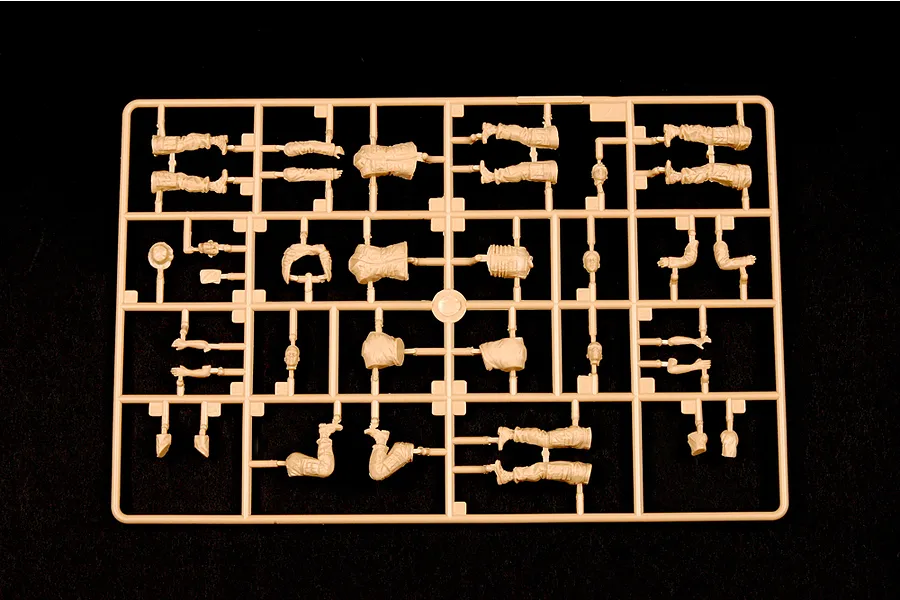 A tan plastic sprue containing various unpainted model soldier parts, including limbs, torsos, and heads, set against a black background.