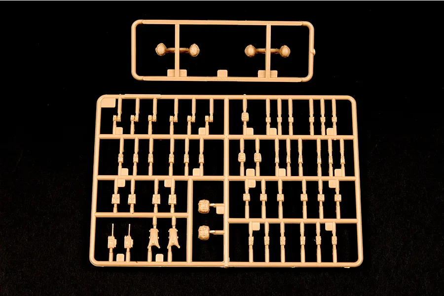 Two tan plastic model kit sprues containing various small military equipment parts on a black background.