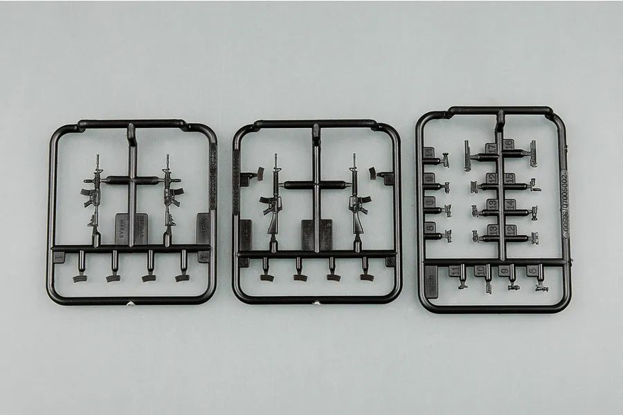 Three black plastic model kit sprues containing miniature rifle and accessory parts for a 1/35 scale military model set.
