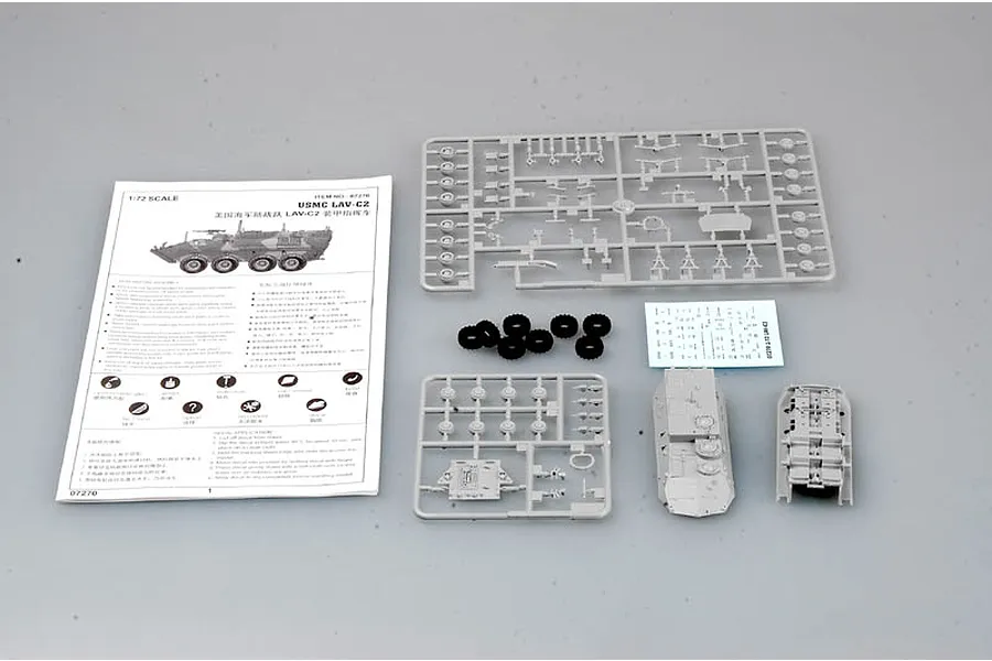 Trumpeter 1/72 scale USMC LAV-C2 model kit contents including instruction manual, plastic sprues, rubber tires, and decal sheet on a grey background.