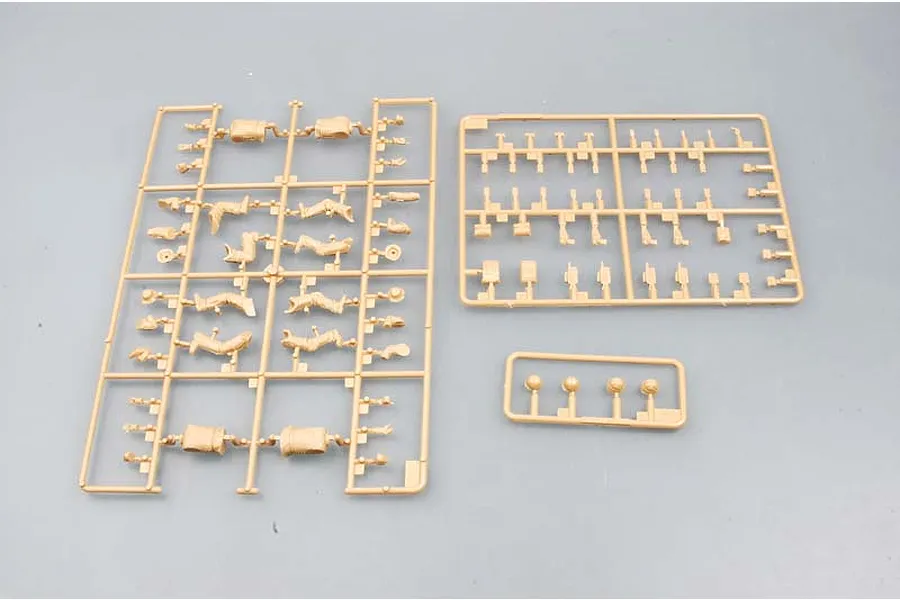 Three plastic model kit sprues containing unpainted tan soldier parts and accessories on a grey background.