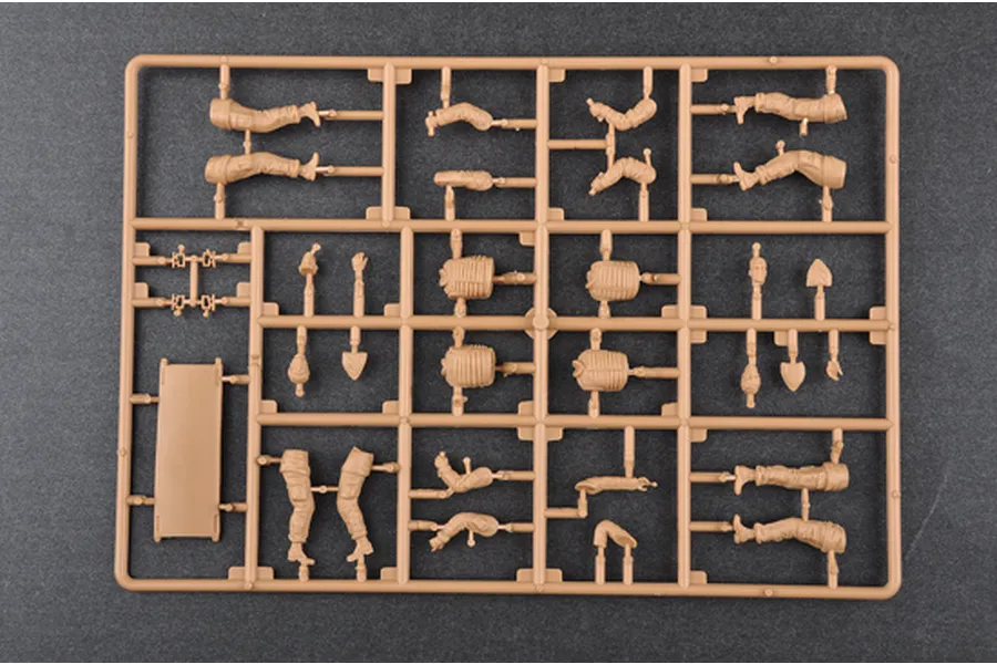 A tan plastic model kit sprue containing various soldier body parts, limbs, and a stretcher for a 1/35 scale military model.