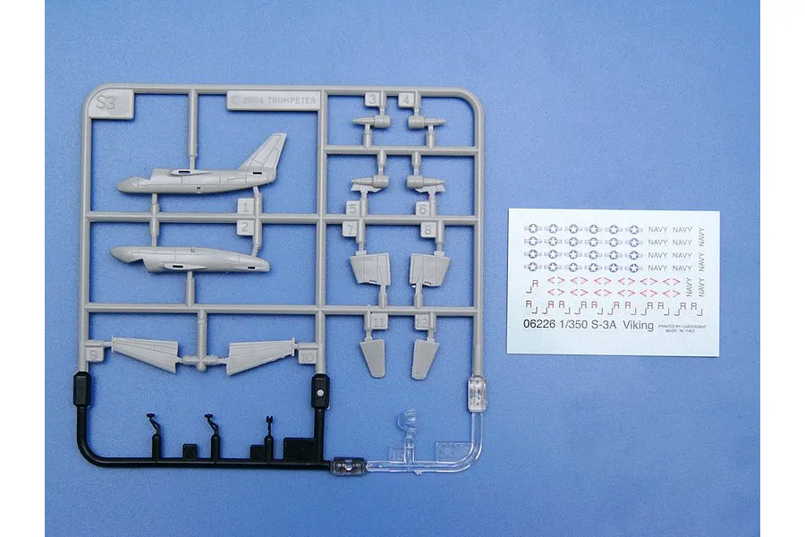 A 1/350 scale plastic model kit sprue of S-3 Viking aircraft parts and a decal sheet on a blue background.