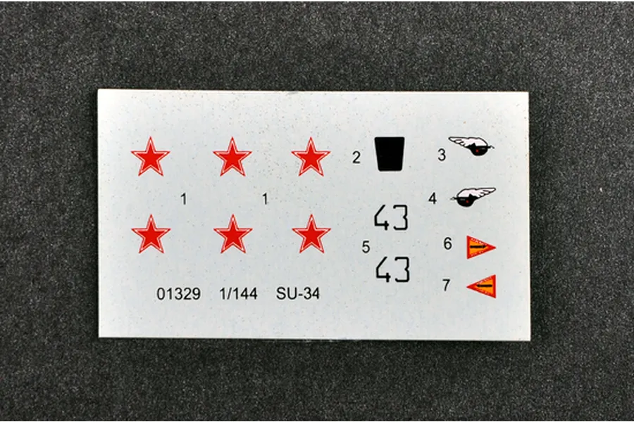 A decal sheet for a 1/144 scale Trumpeter SU-34 model kit featuring red stars, numbers, and small insignia on a white backing.