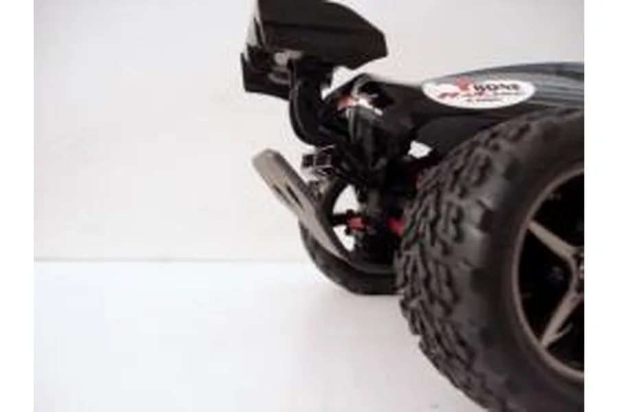 Close-up of a T-Bone Racing rear bumper installed on a 1/16 scale Traxxas E-Revo RC car against a white background.