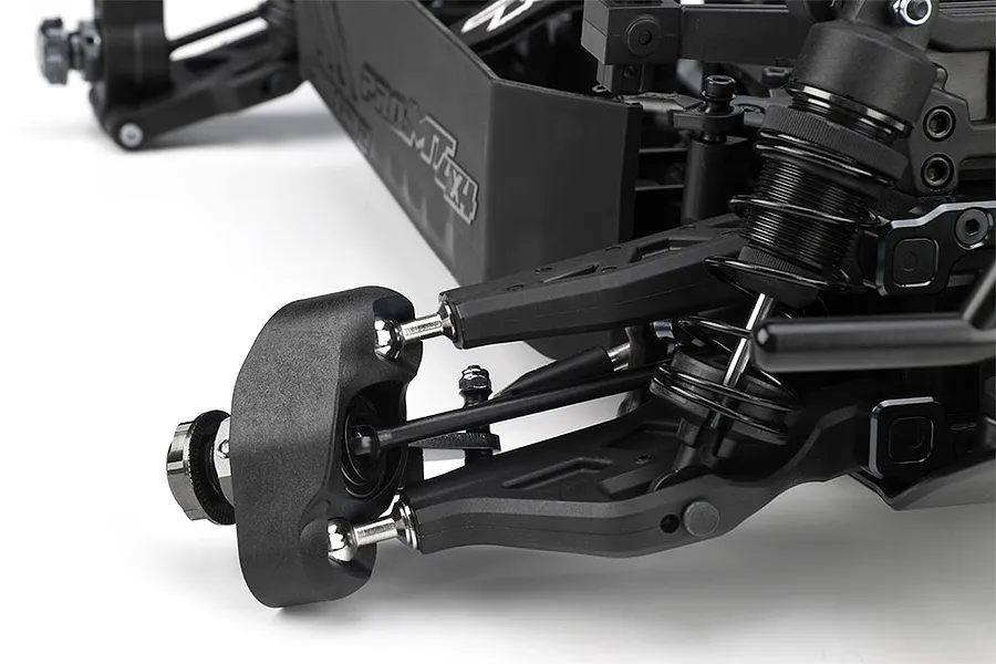 Close-up of the front suspension and chassis of a Pro-Line PRO-MT 4x4 RC truck roller, showing the control arms, shock absorber, and wheel hub.