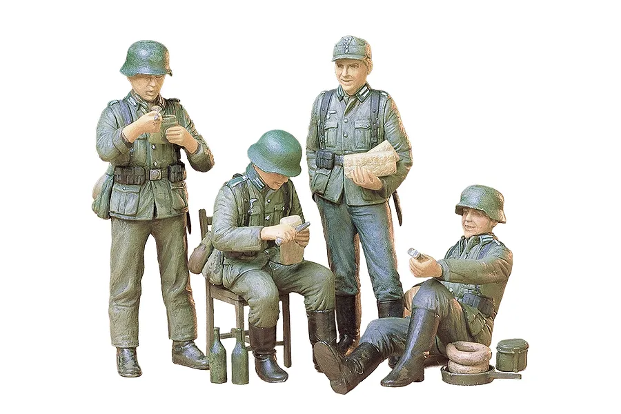 A set of four painted 1/35 scale Tamiya plastic model German soldiers at rest, including figures standing, sitting on a chair, and sitting on the ground.