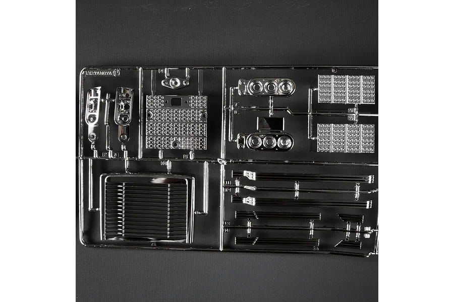A Tamiya P-parts tree featuring chrome-plated plastic RC truck components including a grille, fuel tanks, and step plates.