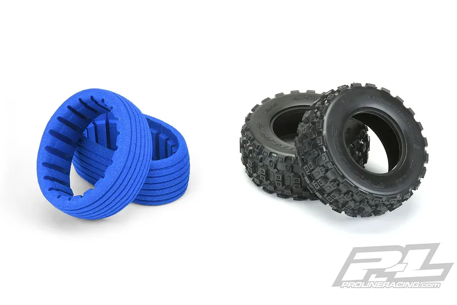 Two black Pro-Line Badlands MX short course RC tyres and two blue foam tyre inserts on a white background.