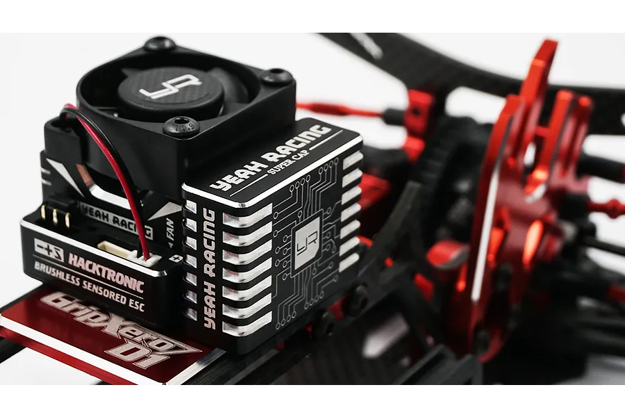 A Yeah Racing Hyper Booster ESC capacitor pack mounted next to a Hacktronic ESC on an RC car chassis.