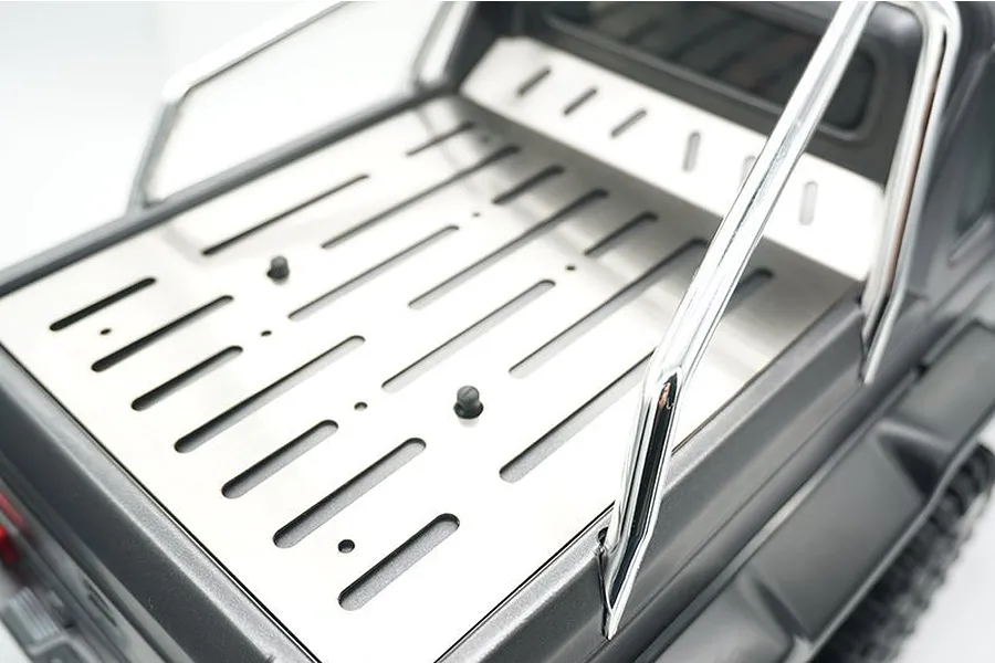 A stainless steel tray cover installed on the bed of a Traxxas TRX-6 Mercedes RC truck, featuring slotted design and chrome roll bar.