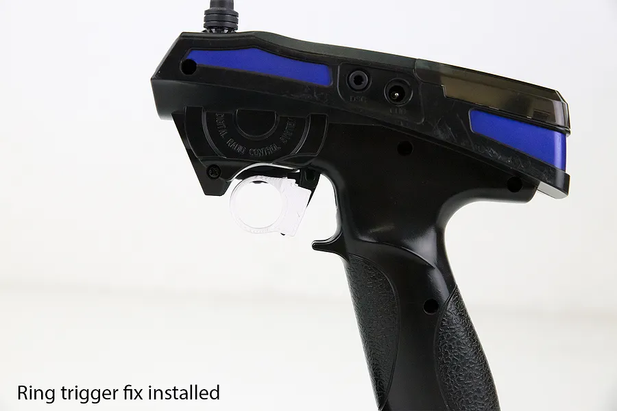 A white 3D-printed ring trigger modification installed on a black FlySky RC transmitter pistol grip.