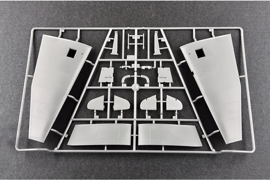 A grey plastic sprue from a model kit containing aircraft wing and tail components on a dark textured background.