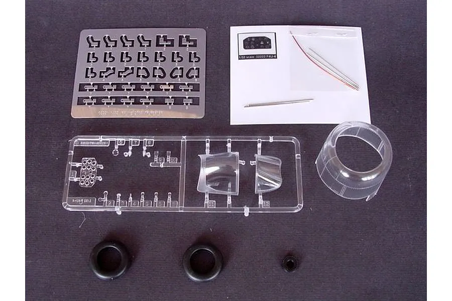 Components for a 1/32 scale Trumpeter Vought F4U-4 Corsair model kit, including photo-etched parts, clear canopy pieces, rubber tires, and small metal rods.